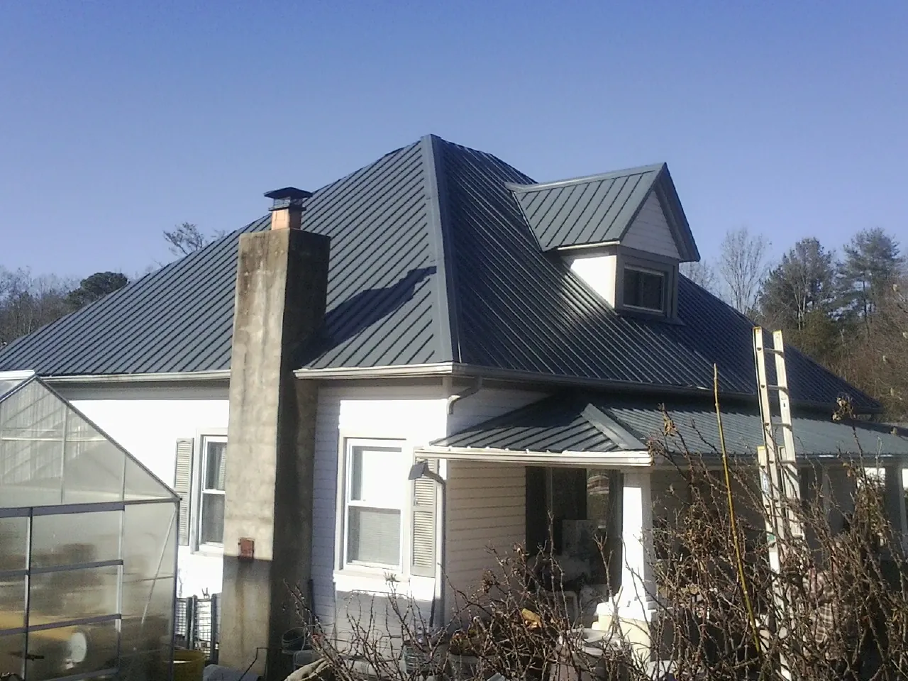 Dark blue standing seam metal roof on a white farmhouse with dormer — Slate & Tile Roof Repair by Roofing Brothers in La Porte