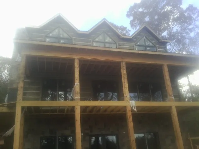 Dormers and porch framing on a large log home under construction — Roof Coating work by our crew in La Porte