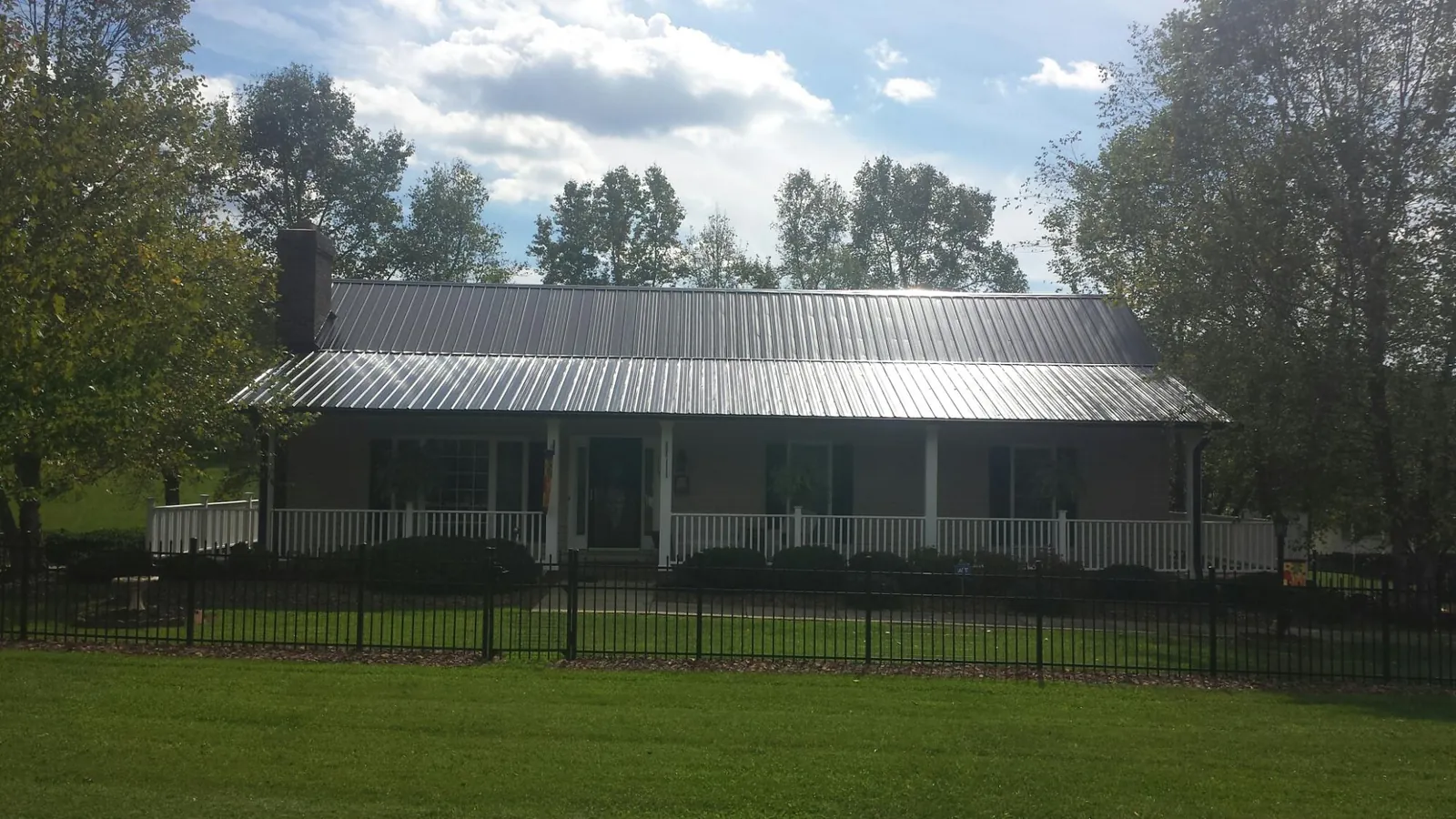 Gray metal roof on a brick ranch with a full width front porch — Gutter Guard Installation work by our crew in La Porte
