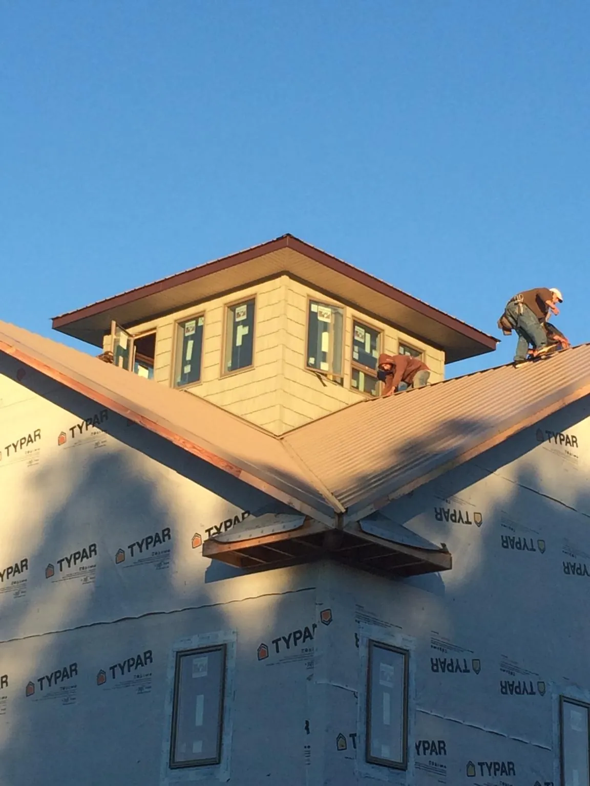Roofers working around a rooftop cupola on a new metal roof at sunset — Roof Waterproofing in La Porte by Roofing Brothers
